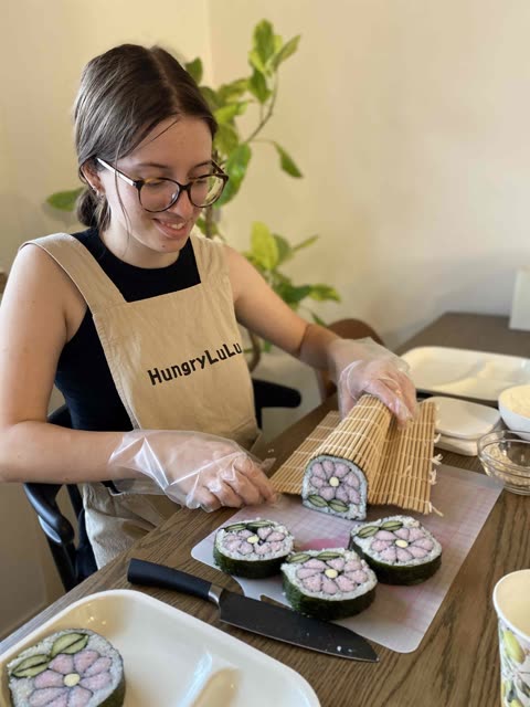 Five people prepare food at a table.