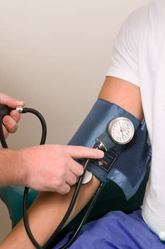 Person's arm with blood pressure cuff; nurse taking reading.